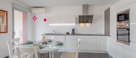 A modern kitchen with white cabinets, a stainless steel range hood, and a built-in oven.