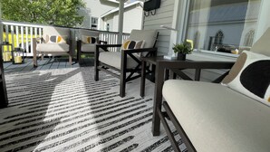 A covered porch with outdoor seating, a table, and a potted plant.