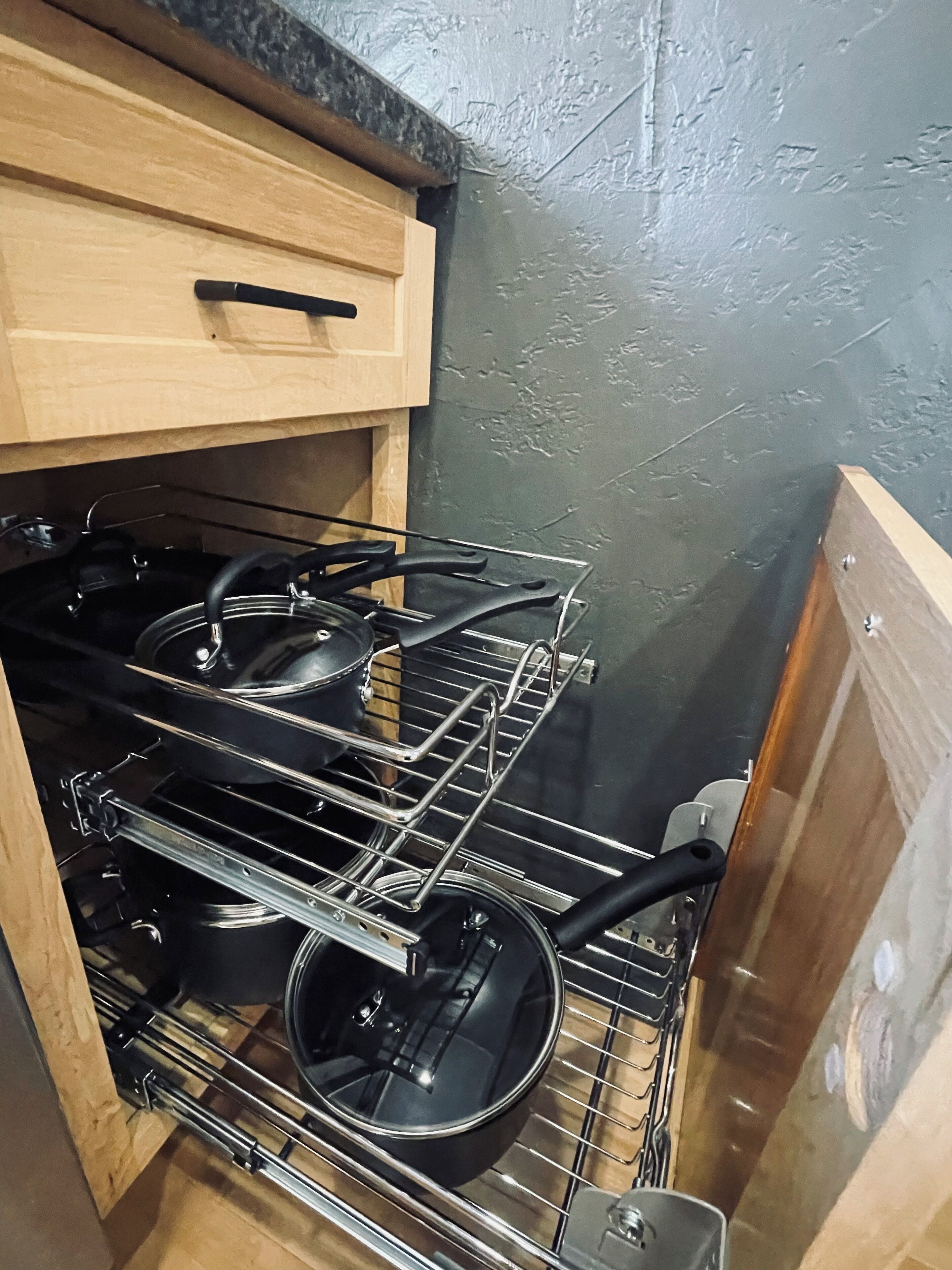 A kitchen with a built-in stove and drying rack for pots and pans.