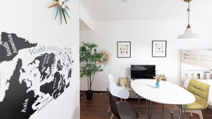 Una habitación moderna con una mesa blanca, sillas, televisor, planta y un mapa mundial en la pared.