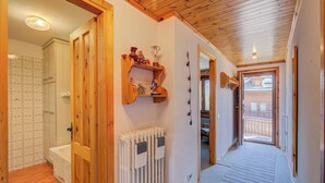 A hallway with wooden doors, a radiator, and a shelf with decorative items. - Casa Ciuk, Livigno, Italy (Livigno)