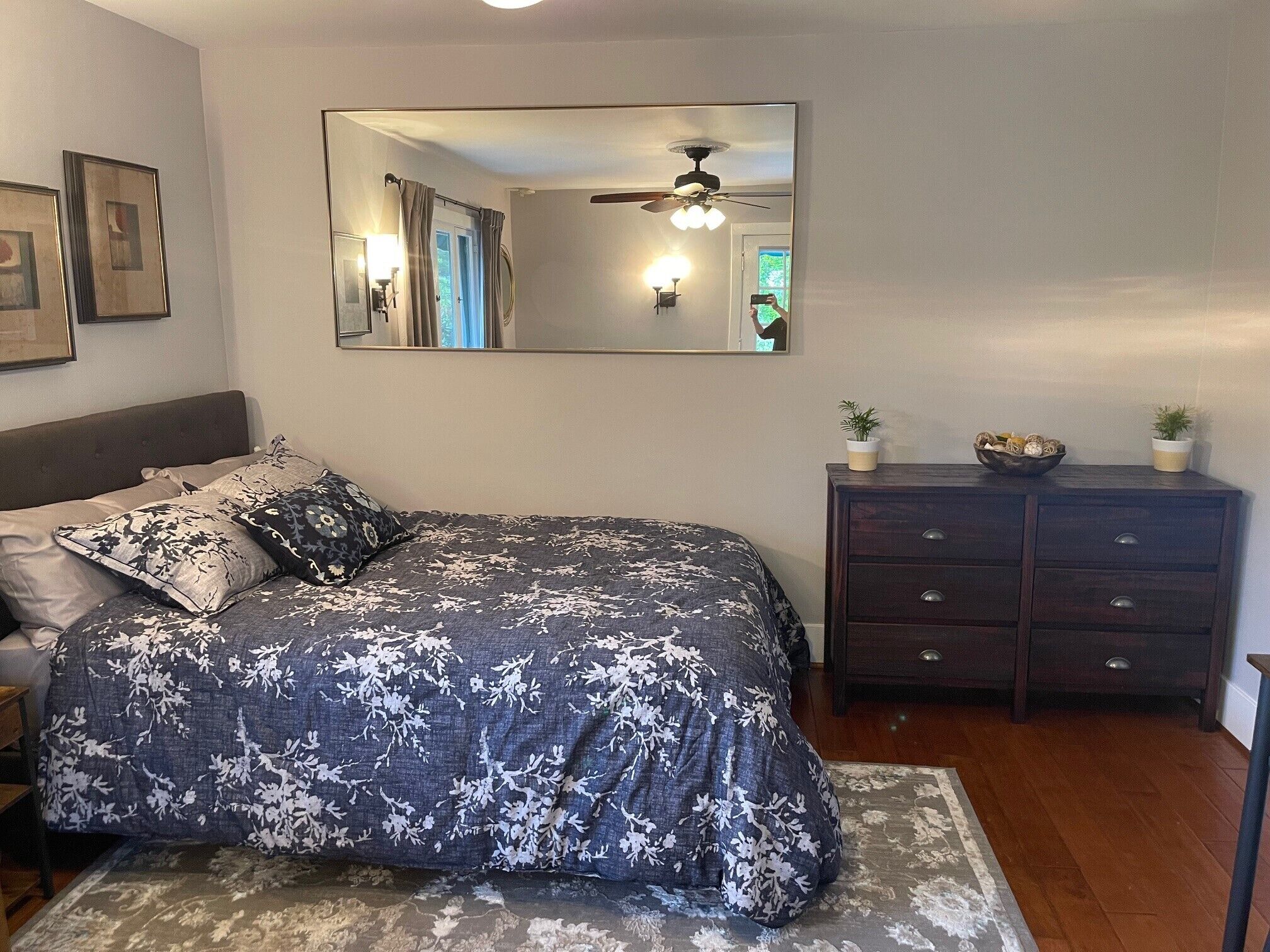 A bedroom with a large bed, a dresser, a mirror, and a ceiling fan.
