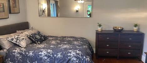 A bedroom with a large bed, a dresser, a mirror, and a ceiling fan.