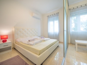 Une chambre à coucher avec un lit, une table de chevet, une lampe et une fenêtre avec des rideaux.