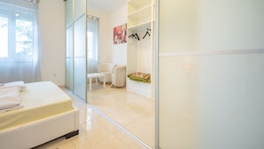 Een moderne slaapkamer met een bed, een stoel, een klein tafeltje en een kledingkast.