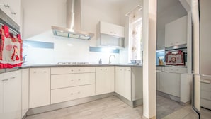 Een moderne keuken met witte kasten, een roestvrijstalen afzuigkap en een betegelde spatwand.