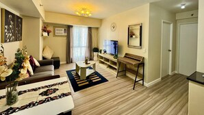 A living room with a sofa, TV, and a small table with a plant. - Condotel Avida Riala Tower 4-1103 (Cebu City)
