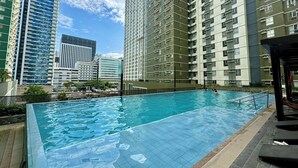 A swimming pool with a tiled deck, surrounded by high-rise residential buildings. - Condotel Avida Riala Tower 4-1103 (Cebu City)