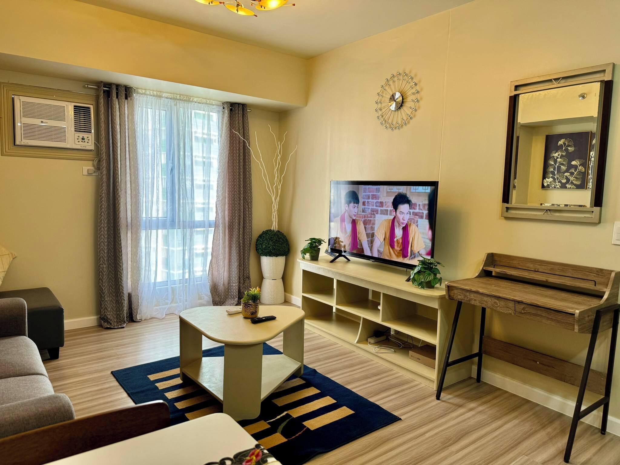 A living room with a sofa, TV, and a small table with decorative items.