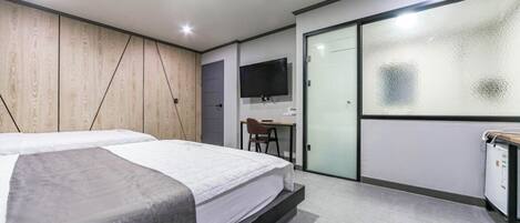 Una habitación de hotel moderna con cama, escritorio, silla y televisor.