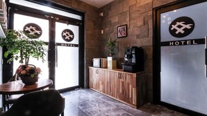 A hotel lobby with a reception desk, a coffee machine, and a potted plant. - The Sharp Hotel (Changwon)