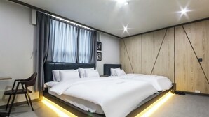 A modern bedroom with a large bed, bedside tables, a chair, and a wooden accent wall. - The Sharp Hotel (Changwon)