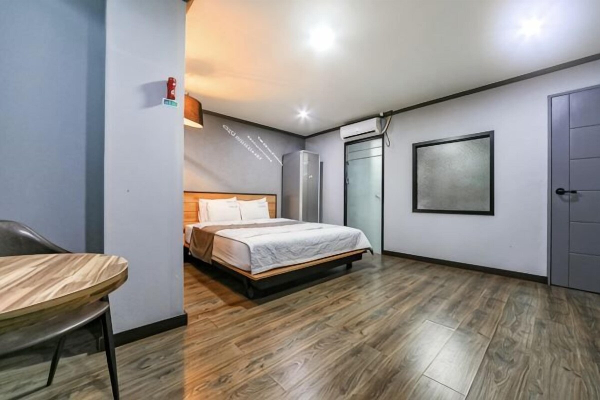 A bedroom with a bed, a desk, a wardrobe, and a door.