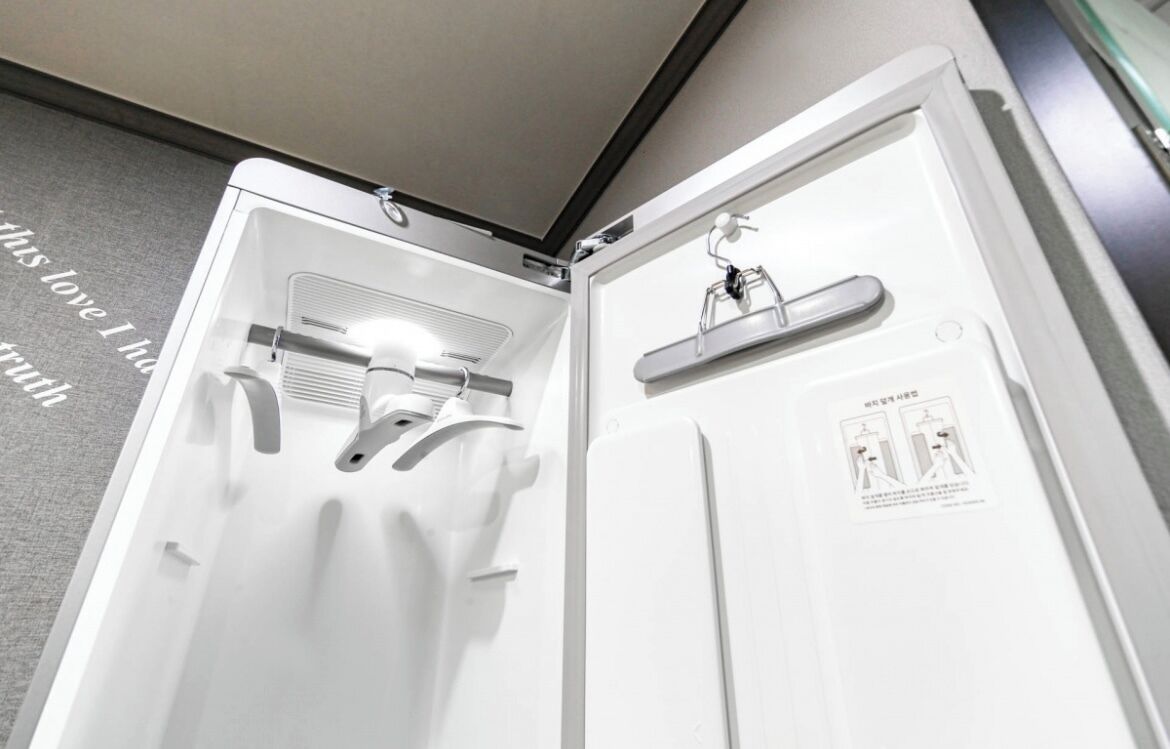 A white, modern bathroom with a shower, a towel rack, and a sign with instructions.