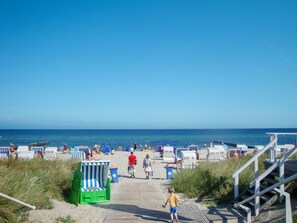 A beach with beach chairs and a wooden staircase leading to the beach.