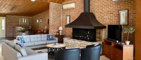 A cozy living room with a fireplace, a sofa, a coffee table, and a TV stand.