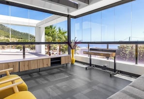 A modern interior with large windows, a wooden bench, and a plant.