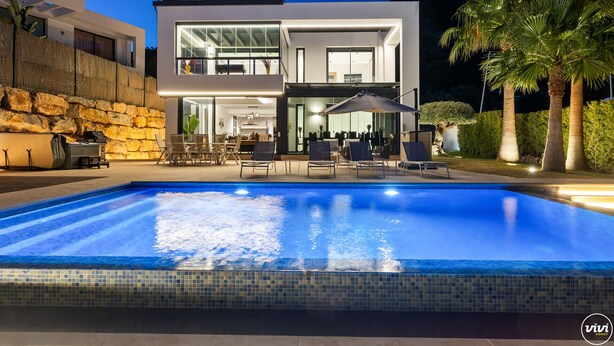 A modern two-story house with a swimming pool, outdoor seating, and a stone wall. - Villa Yara | Pool - BBQ - Bar (Mijas)