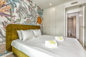 A hotel room with a large bed, a headboard, a wardrobe, and a bathroom visible through an open door.