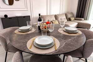 A dining table set with plates, cutlery, and glasses, surrounded by upholstered chairs.