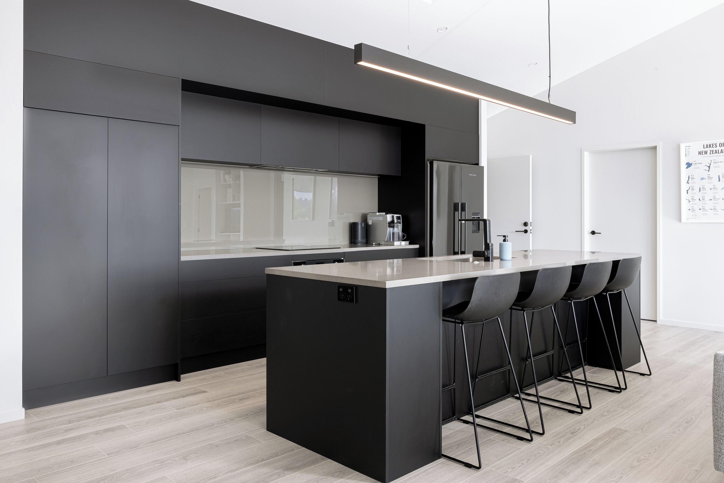 A modern kitchen with a central island, bar stools, and a coffee machine.