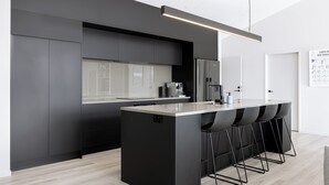 Eine moderne Küche mit einer zentralen Kochinsel, Barhocker und einer Kaffeemaschine.