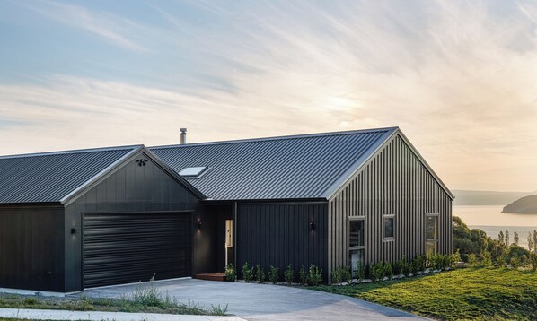 Une maison moderne à l’extérieur sombre, avec un garage et une grande fenêtre.