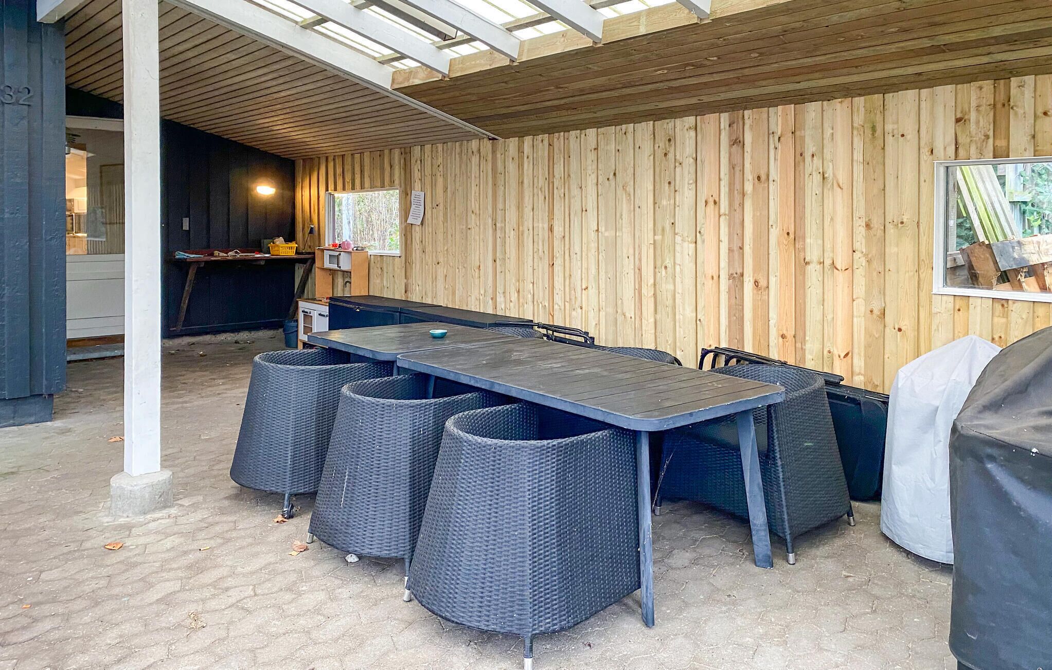An outdoor patio with a wooden table and chairs, a pergola overhead, and a view of the surrounding area.