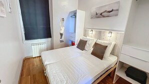 Et moderne soveværelse med en stor seng, et vindue, en radiator og et billede på væggen.