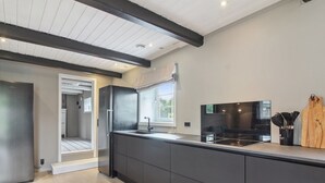 Eine moderne Küche mit dunklen Schränken, einem Edelstahlkühlschrank, einem schwarzen Herd und einem Fenster, das für natürliches Licht sorgt.
