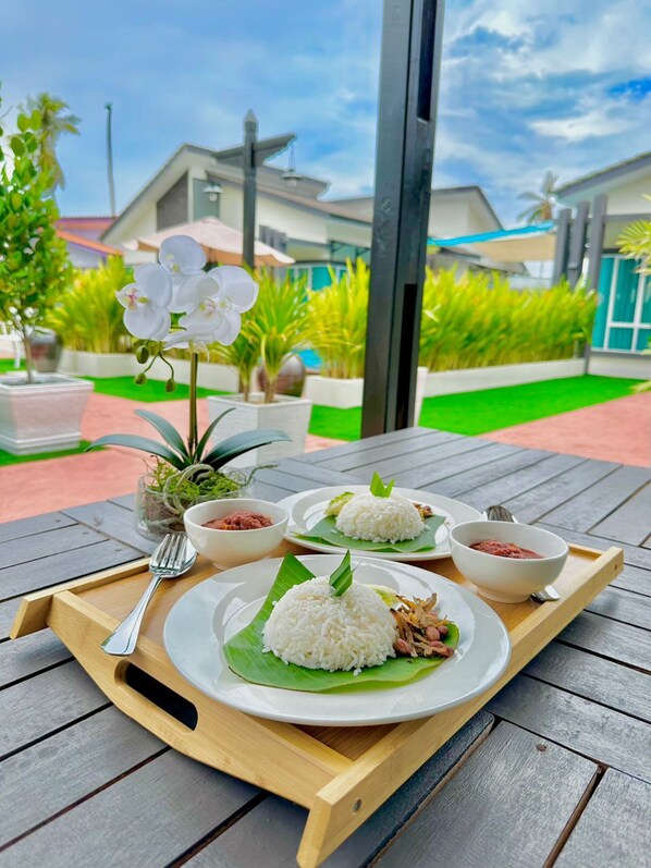 A tray with three plates of rice and two bowls of sauce, set on a wooden table outdoors. - Tijami Villa & Resort (Setiu)