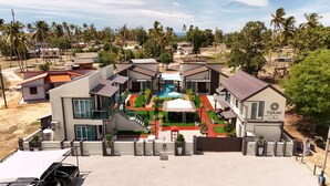 A modern villa with a swimming pool, multiple balconies, and a well-maintained garden. - Tijami Villa & Resort (Setiu)