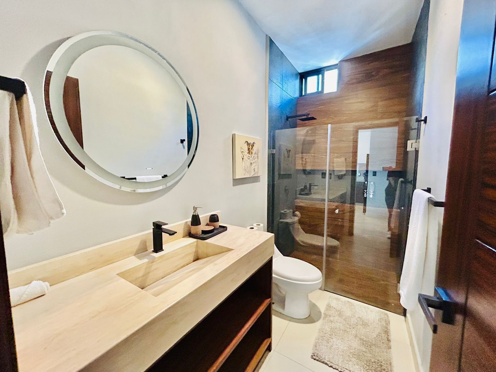 Une salle de bain moderne avec un grand miroir, un meuble-lavabo en bois, des toilettes et une cabine de douche en verre.