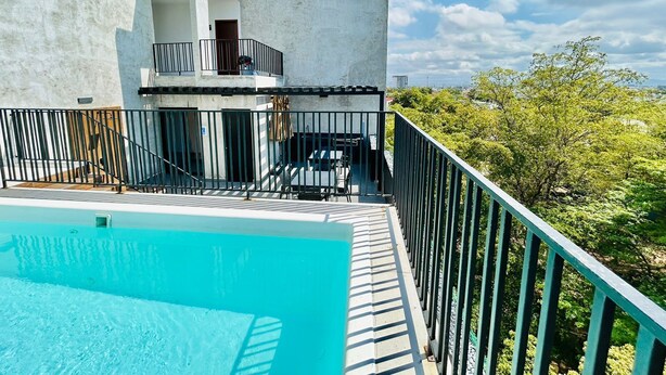 A modern building with a pool, a balcony, and a view of greenery. - Cipres Apartments (Mazatlán)