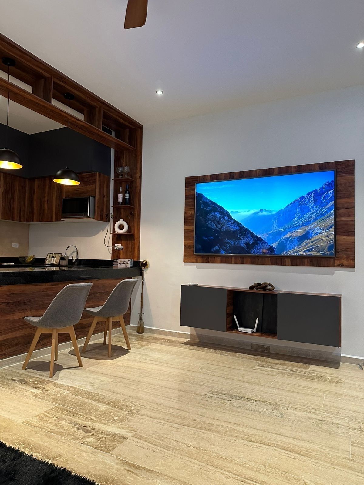 Una cocina moderna con muebles de madera, microondas integrado y una zona de comedor con dos sillas.
