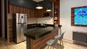 A modern kitchen with a central island, stainless steel appliances, wooden cabinetry, and a built-in TV. - Getaway Rooftop Apartment. Pet Friendly!! (Mérida)