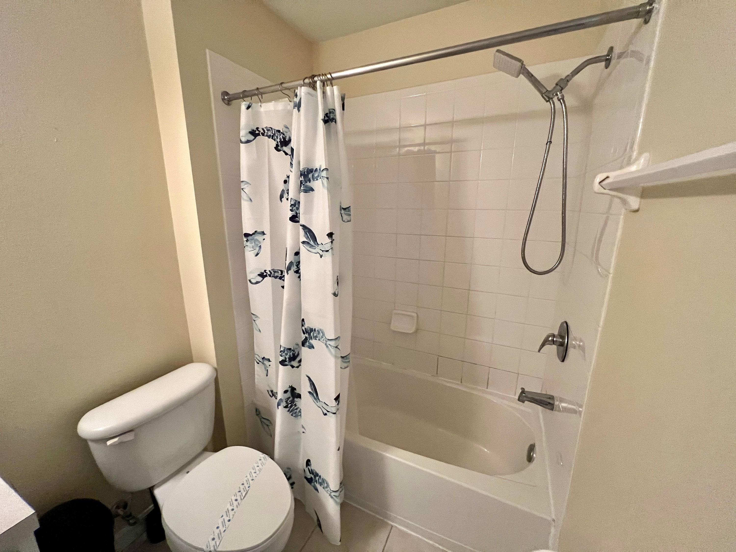A bathroom with a toilet, a shower with a glass door, and a bathtub.