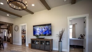 A spacious living room with a large flat-screen TV, wooden flooring, a dark rug, and a modern chandelier. - House in the heart of Darby, Montana
Fully remodeled. (Darby)