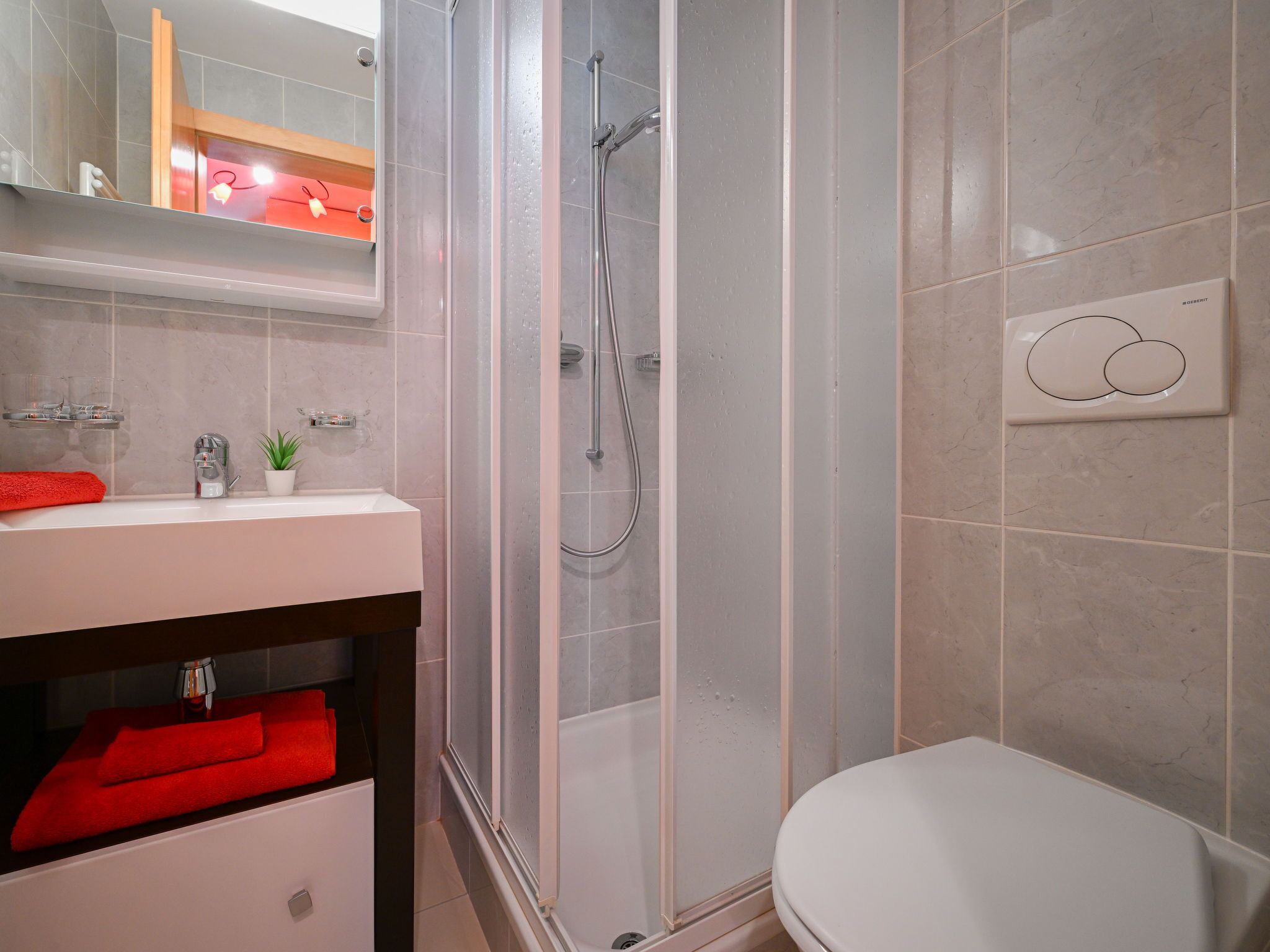 Een moderne badkamer met een douchecabine van glas, een wit wastafelmeubel en een toilet.