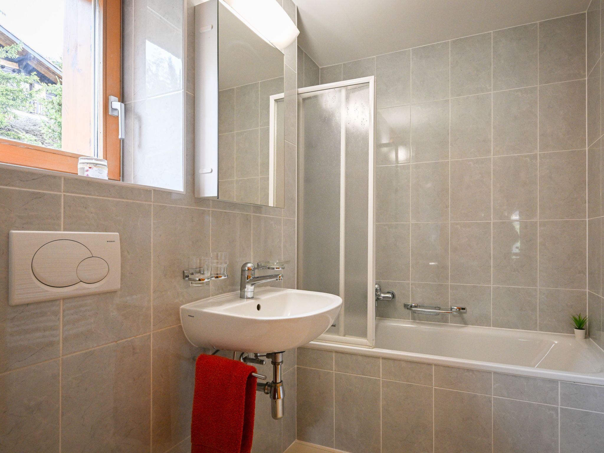 A modern bathroom with a white sink, a glass shower enclosure, and a bathtub.