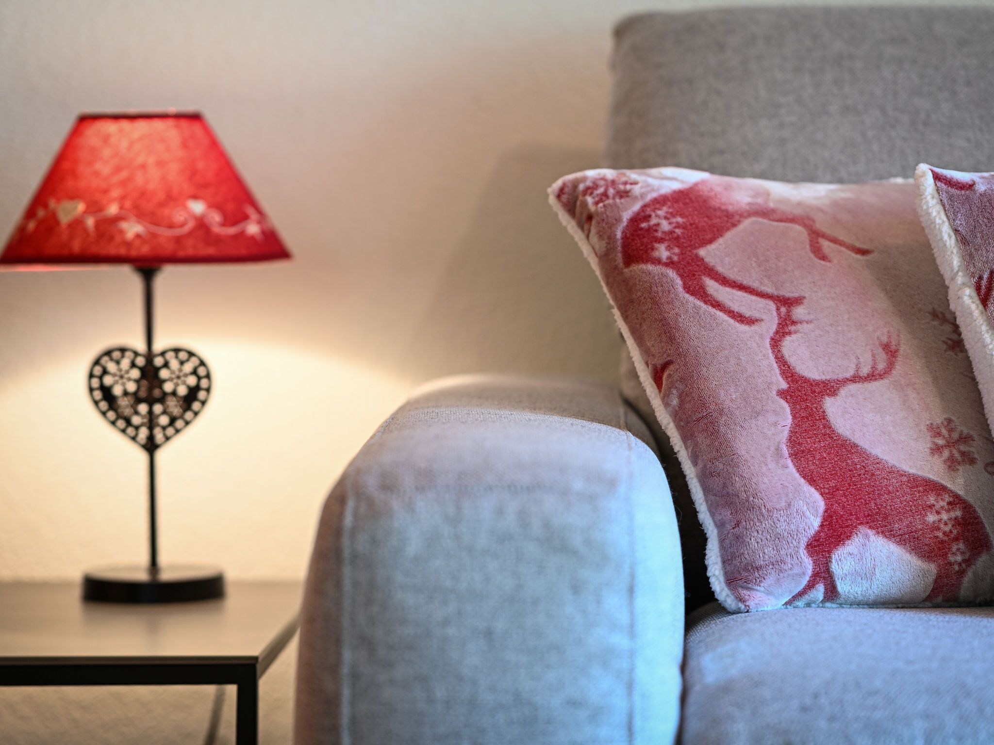A sofa with a heart-shaped lamp and a cushion with a reindeer design.