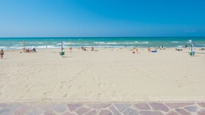 Een strand met heldere lucht, zandstrand en enkele mensen.