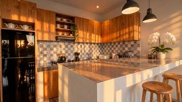 Cocina moderna con armarios de madera, una isla grande e iluminación colgante.