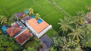 Vista aérea de una propiedad con varias edificaciones, piscina y campos verdes exuberantes.