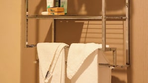 A metal towel rack with folded towels and toiletries. - Premium Queen Room in Motel in SOMA, Free Parking,Breakfast,15 Min to Moscone (San Francisco)
