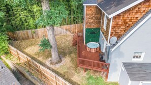 A backyard with a hot tub, wooden deck, and a fenced area.