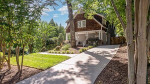 A two-story house with a covered front porch, a driveway, and a well-maintained lawn. - Luxury South End Retreat - Hot Tub - 4 Bedrooms (Charlotte)