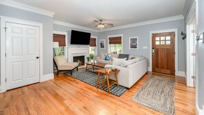 A living room with a fireplace, a sofa, a coffee table, and a television. - Luxury South End Retreat - Hot Tub - 4 Bedrooms (Charlotte)