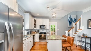 A modern kitchen with white cabinets, stainless steel appliances, and a wooden floor. - Luxury South End Retreat - Hot Tub - 4 Bedrooms (Charlotte)