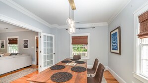 A dining area with a wooden table, black placemats, brown chairs, and a hanging light fixture. - Luxury South End Retreat - Hot Tub - 4 Bedrooms (Charlotte)